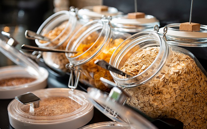 Gesundes Frühstück im Hotel mit Müsli, Haferflocken und Cornflakes in dekorativen Glasbehältern